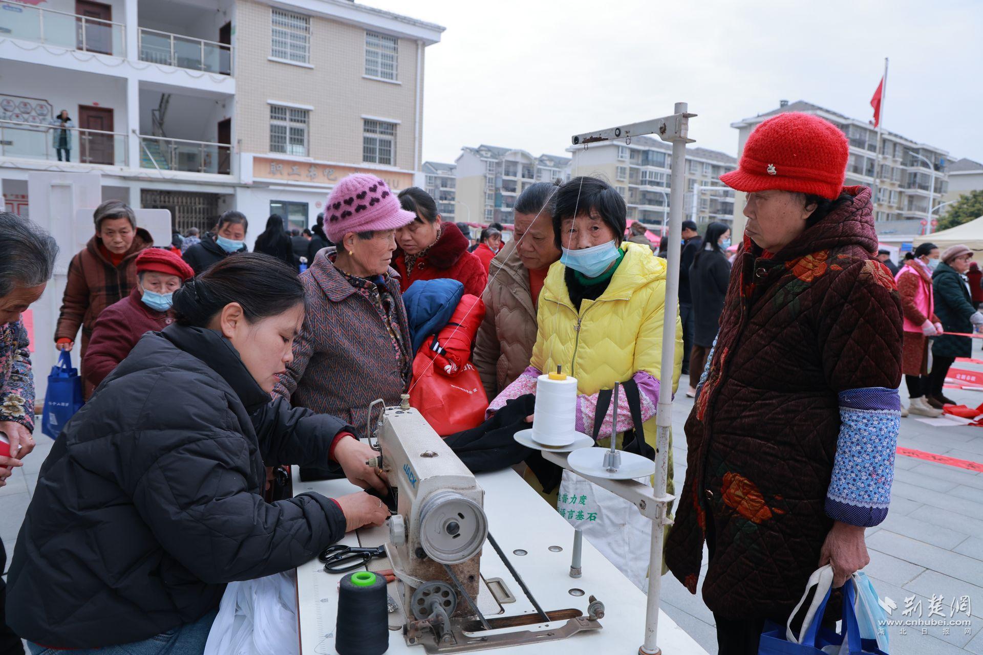 衣物縫補(bǔ)攤前，志愿者飛針走線為居民修補(bǔ)破損衣物.jpg.jpg
